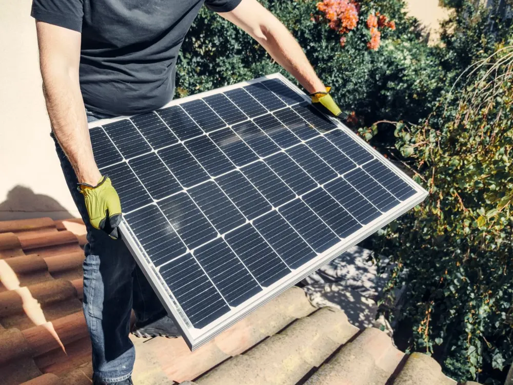 Monteur installeert zonnepanelen op een schuin dak